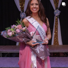 A woman in pink wearing a Miss UL Lafayette sash and holding flowers