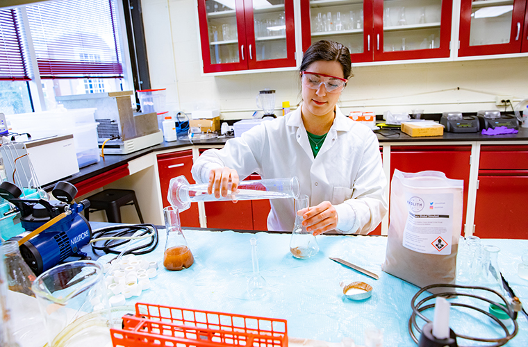 student pouring chemical from beaker