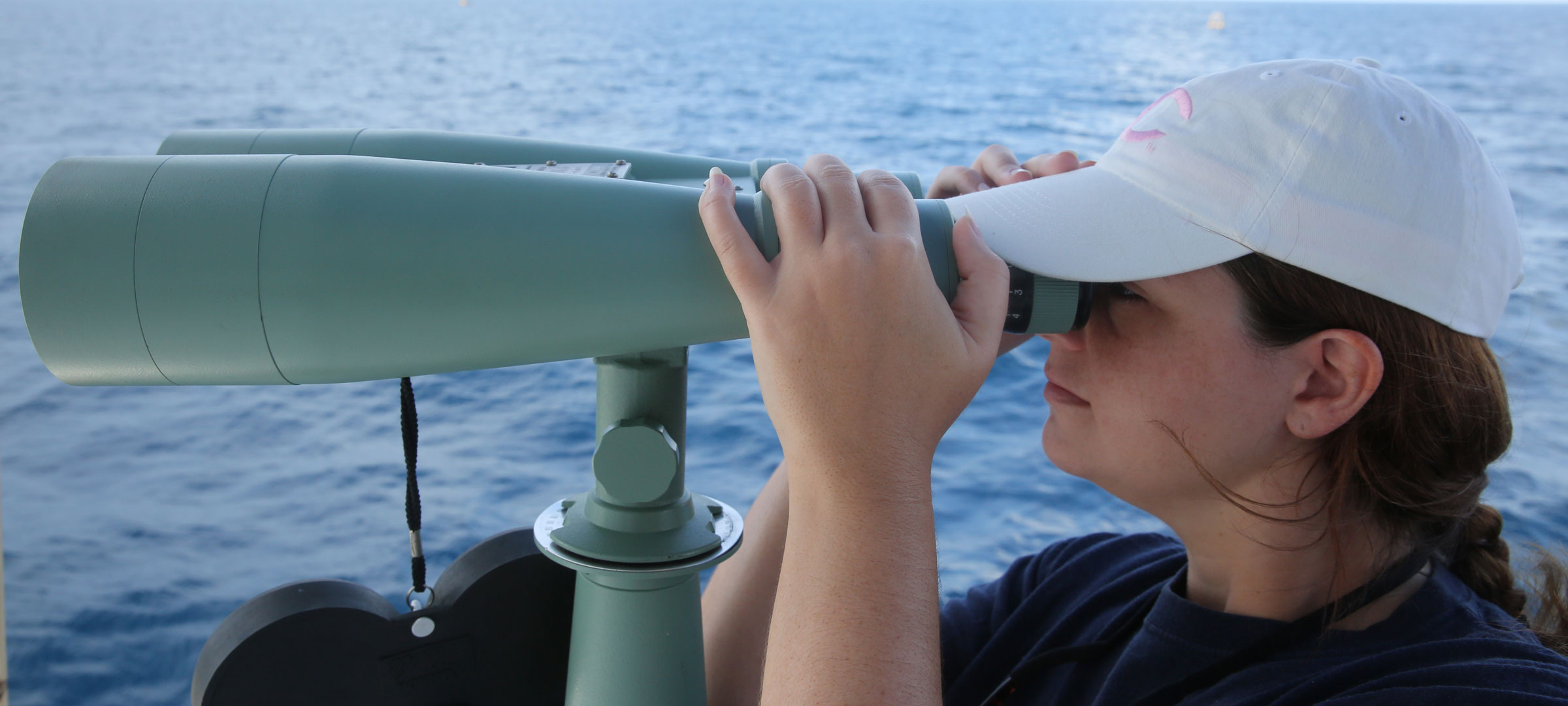 A University of Louisiana at Lafayette research faculty member looks through binoculars over water during a research trip into the Gulf of Mexico