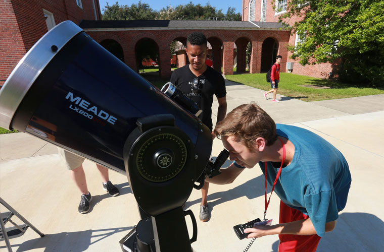 Physics and geophysics majors study the stars and planets through a telescope in the University of Louisiana at Lafayette quad