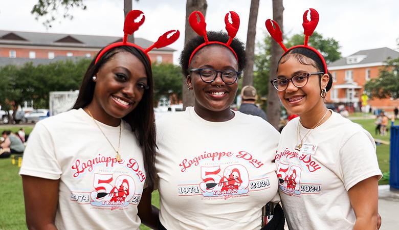 Three students wearing Laginiappe Day 50th anniversary shirts