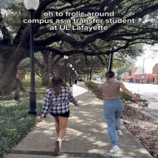 Two UL students skip away from the camera underneath big trees
